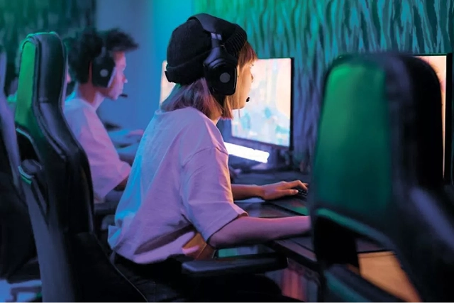 Jonge gamers spelen videogames op pc's met headsets in een esports gamingruimte.
