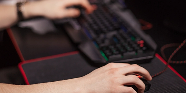 Handen van een gamer die een mechanisch toetsenbord en gamingmuis gebruikt tijdens het spelen.