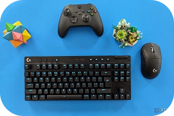 Gaming setup met Logitech G toetsenbord, muis en controller op een blauwe achtergrond.