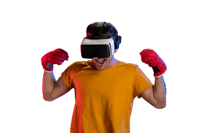 Een persoon in een geel shirt met een VR-bril en rode bokshandschoenen, die enthousiast juicht met opgeheven armen tegen een donkere achtergrond.